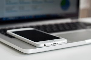 A phone laying on top of a laptop.