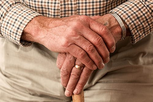 An elderly man crossing his hands on his cane