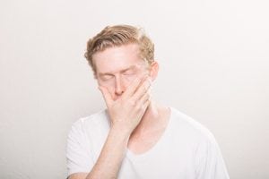 guy with hand over his mouth in frustration