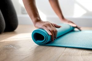 rolling up a teal yoga mat