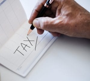 Man filling out checkbook with "Tax" written on it