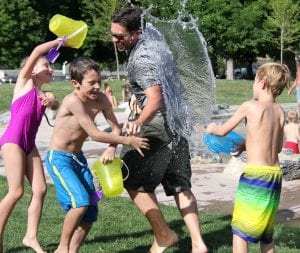Older man and children playing with buckets of water outside
