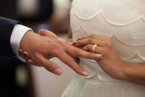 Wife placing wedding ring on groom's finger