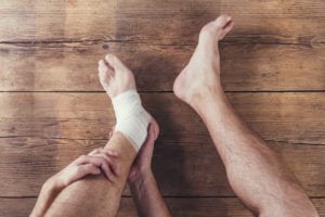 Unrecognizable injured runner sitting on a wooden floor background