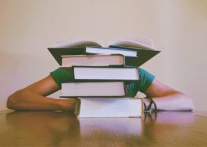 student hiding behind books
