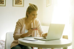 Cheerful woman paying bills at home. E-banking.