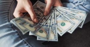 woman in jeans holding cash dollars 100 dollar bills fingernails