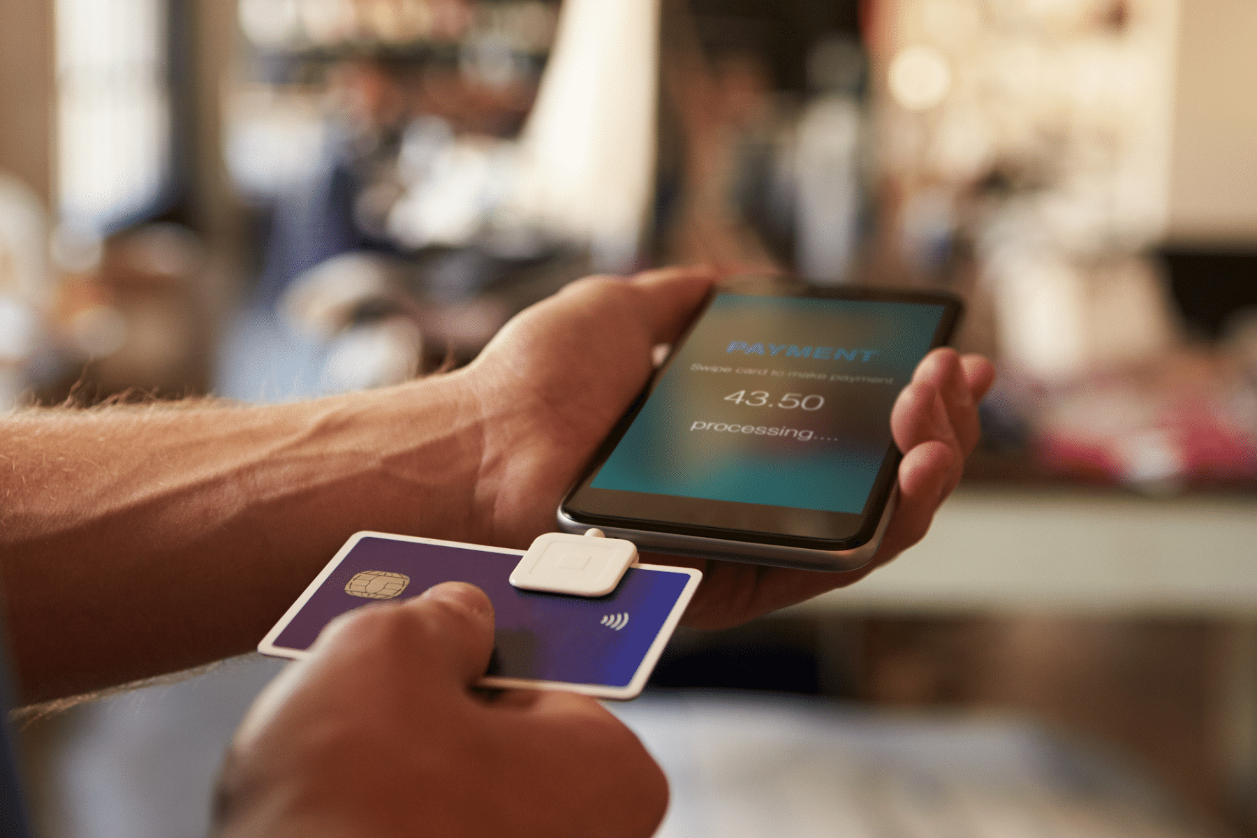 Person swiping credit card on phone with Square reader