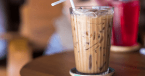 Iced latte with a straw on top of coaster sitting on table
