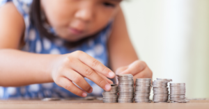 young child stacking coins on a table