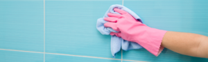 pink gloved hand scrubbing blue tile