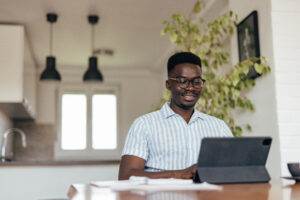 Happy adult man, paying his bills online, while working from home.